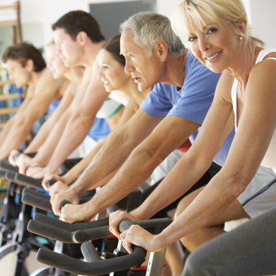 Senior Woman Cycling In Spinning Class In Gym